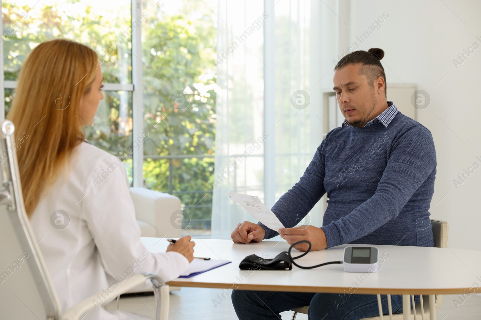 Photo of Nutritionist consulting overweight man at table in clinic