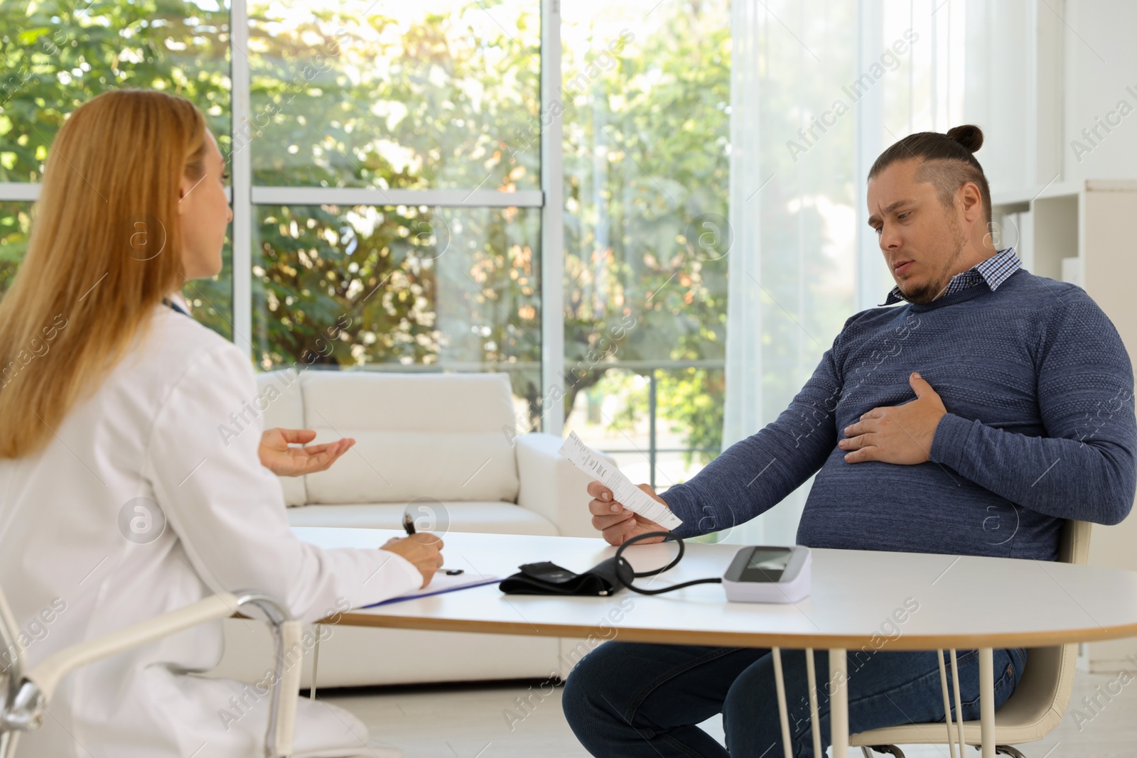 Photo of Nutritionist consulting overweight man at table in clinic