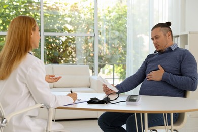 Photo of Nutritionist consulting overweight man at table in clinic