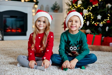 Photo of Cute little kids with Santa hats in room decorated for Christmas