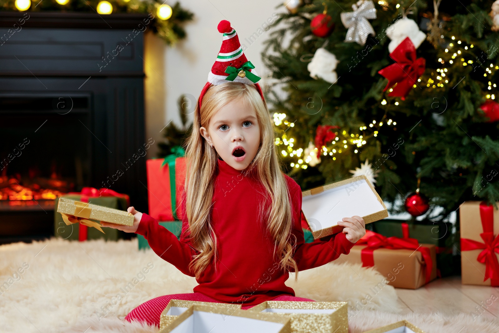 Photo of Little girl opening Christmas gift on floor at home