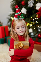 Photo of Little girl with Christmas gift at home