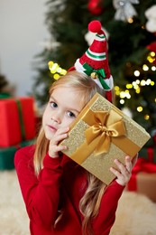 Photo of Little girl with Christmas gift at home