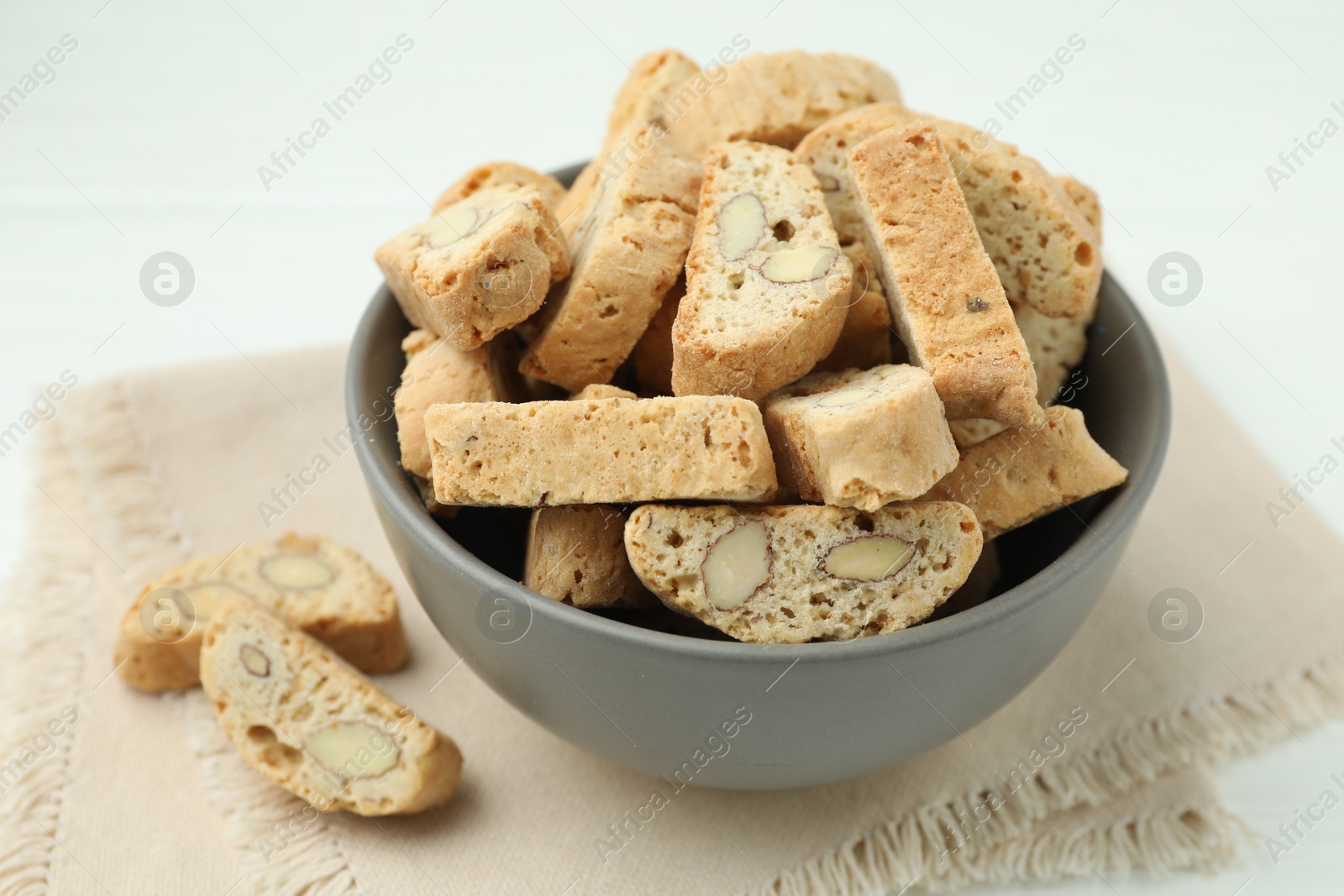 Photo of Traditional Italian almond biscuits (Cantucci) in bowl on table, closeup