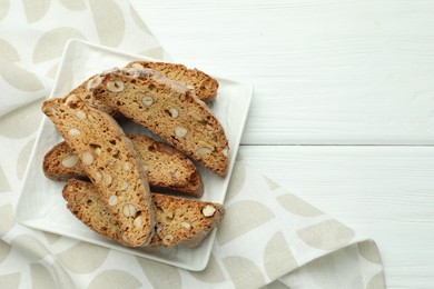 Traditional Italian almond biscuits (Cantucci) on white wooden table, top view. Space for text