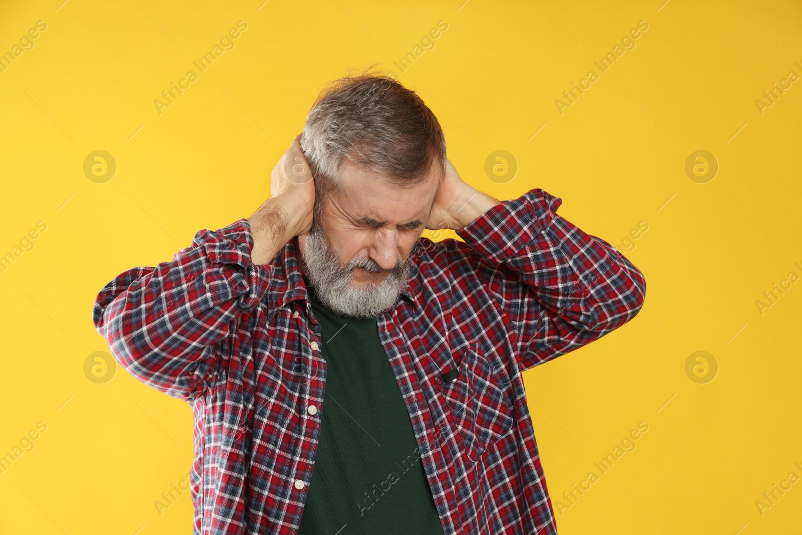 Photo of Senior man covering his ears on orange background