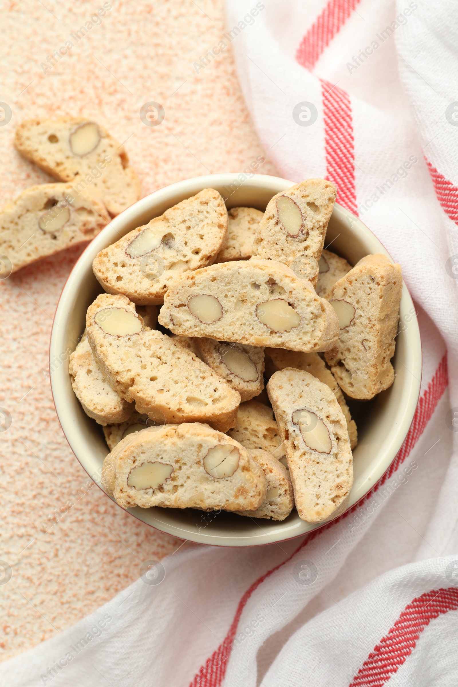 Photo of Traditional Italian almond biscuits (Cantucci) in bowl on beige textured table, top view