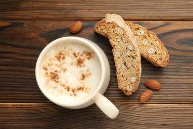 Traditional Italian almond biscuits (Cantucci), nuts and cup of coffee on wooden table, flat lay