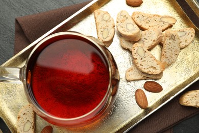 Photo of Traditional Italian almond biscuits (Cantucci), nuts and cup of tea on grey table, flat lay