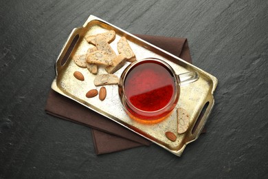 Photo of Traditional Italian almond biscuits (Cantucci), nuts and cup of tea on grey textured table, top view