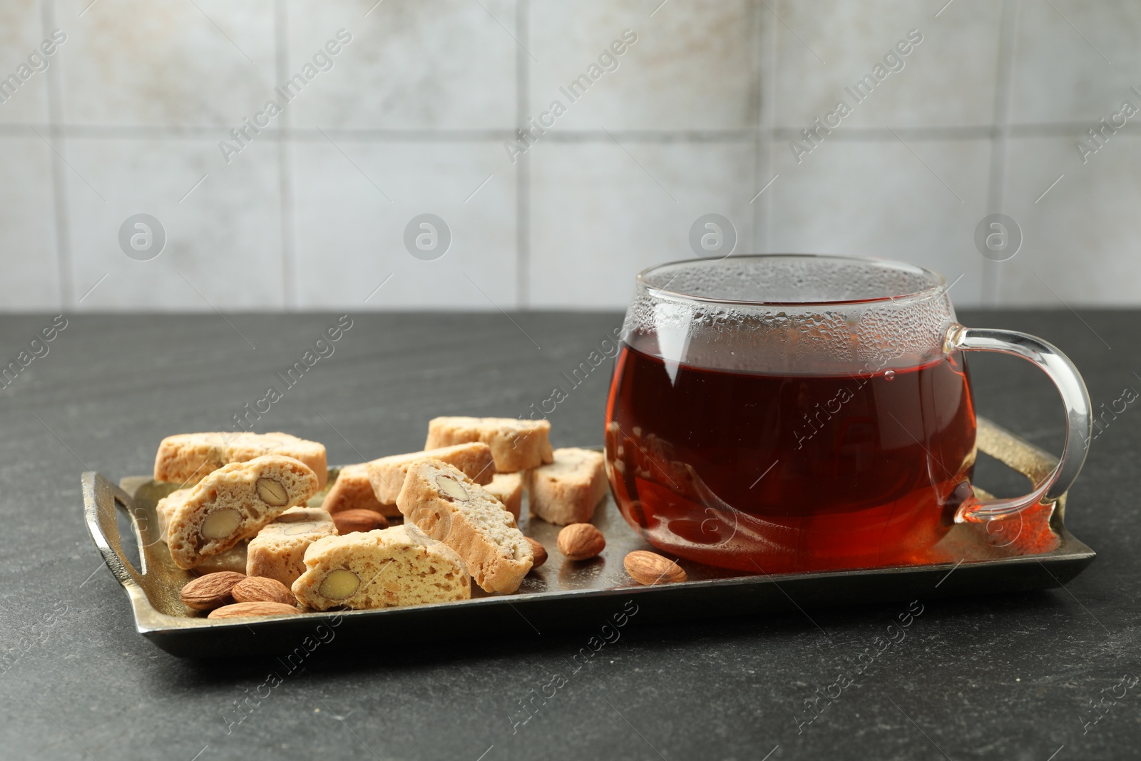 Photo of Traditional Italian almond biscuits (Cantucci), nuts and cup of tea on grey textured table, closeup