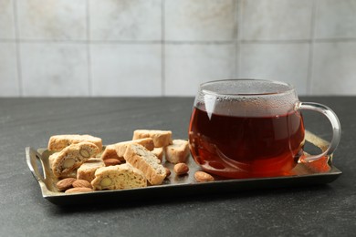 Traditional Italian almond biscuits (Cantucci), nuts and cup of tea on grey textured table, closeup