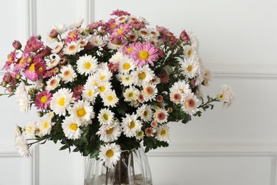 Photo of Vase with beautiful flowers near white wall, closeup