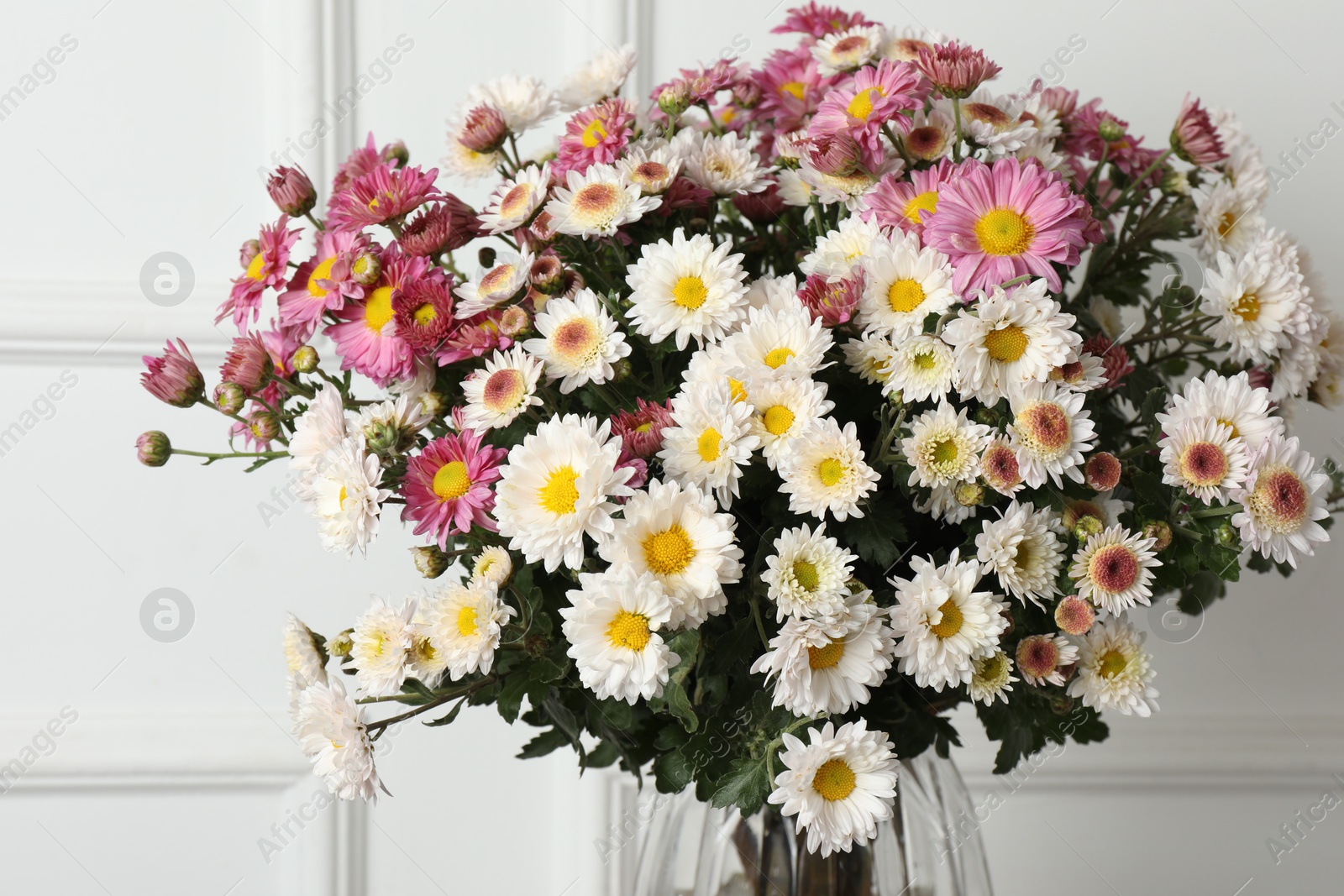 Photo of Vase with beautiful flowers near white wall, closeup