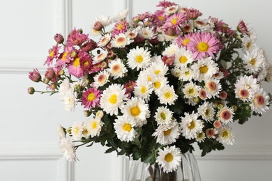 Photo of Vase with beautiful flowers near white wall, closeup