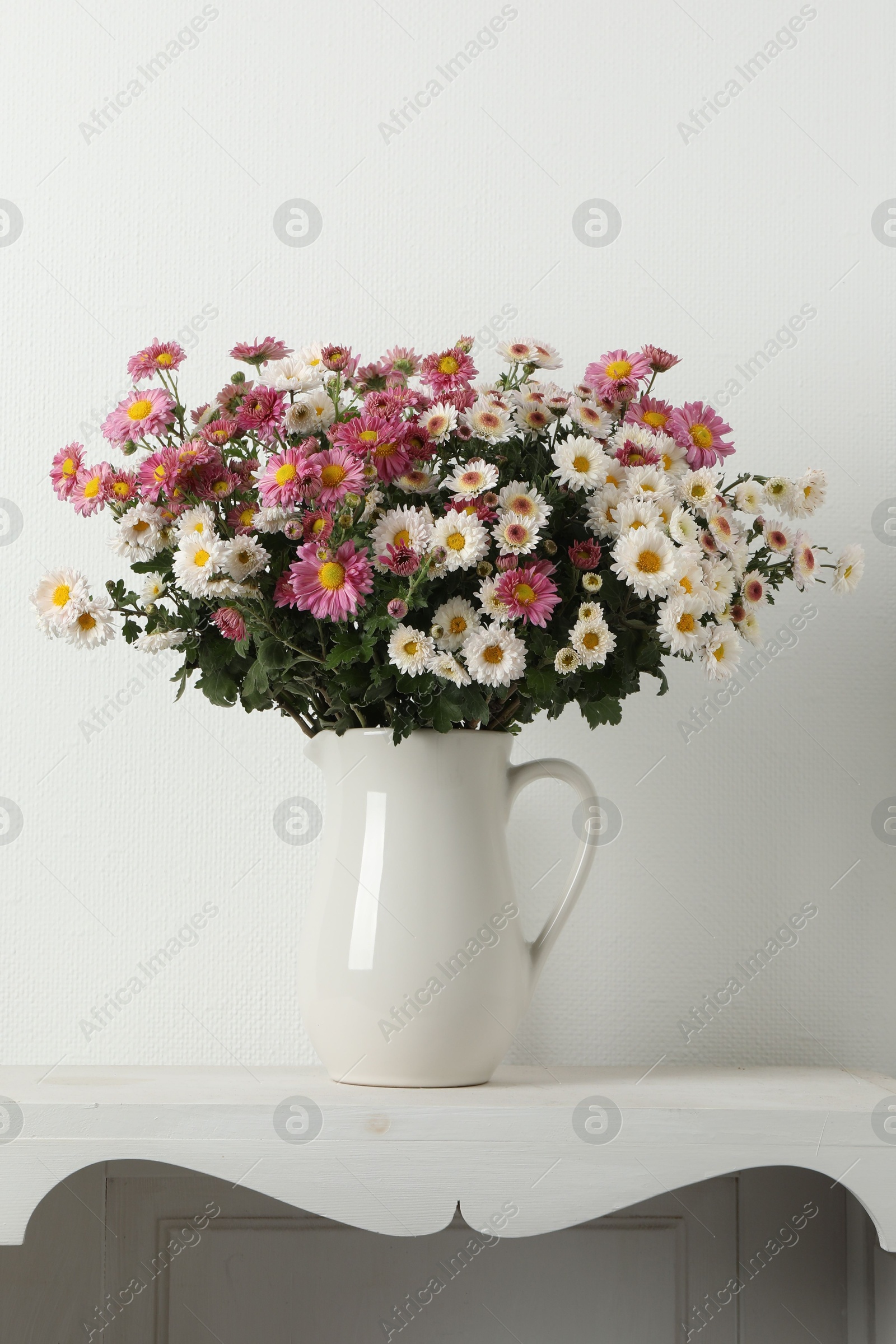 Photo of Vase with beautiful flowers on white shelving unit