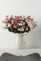 Vase with beautiful flowers on white shelving unit