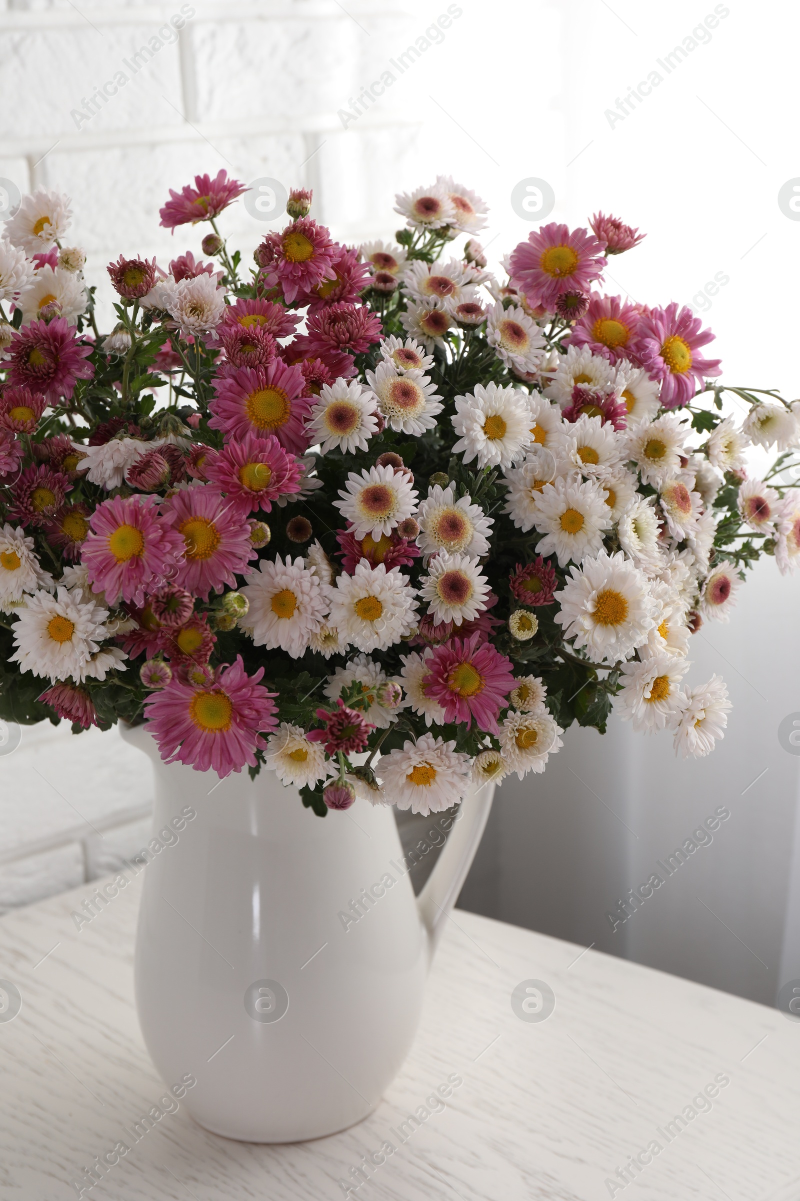 Photo of Vase with beautiful flowers on white wooden table