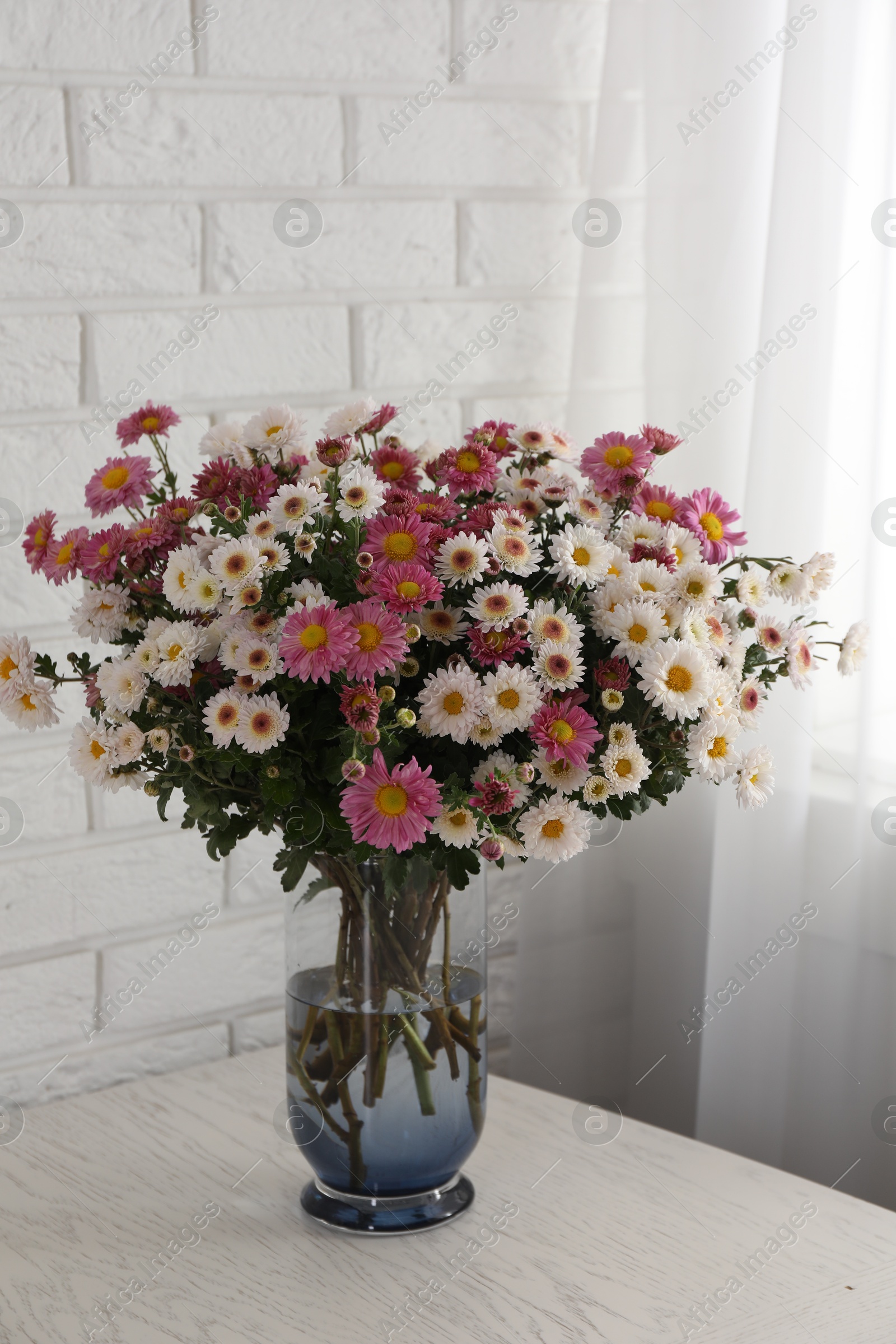 Photo of Vase with beautiful flowers on white wooden table