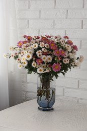 Photo of Vase with beautiful flowers on white wooden table