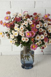 Photo of Vase with beautiful flowers on white wooden table