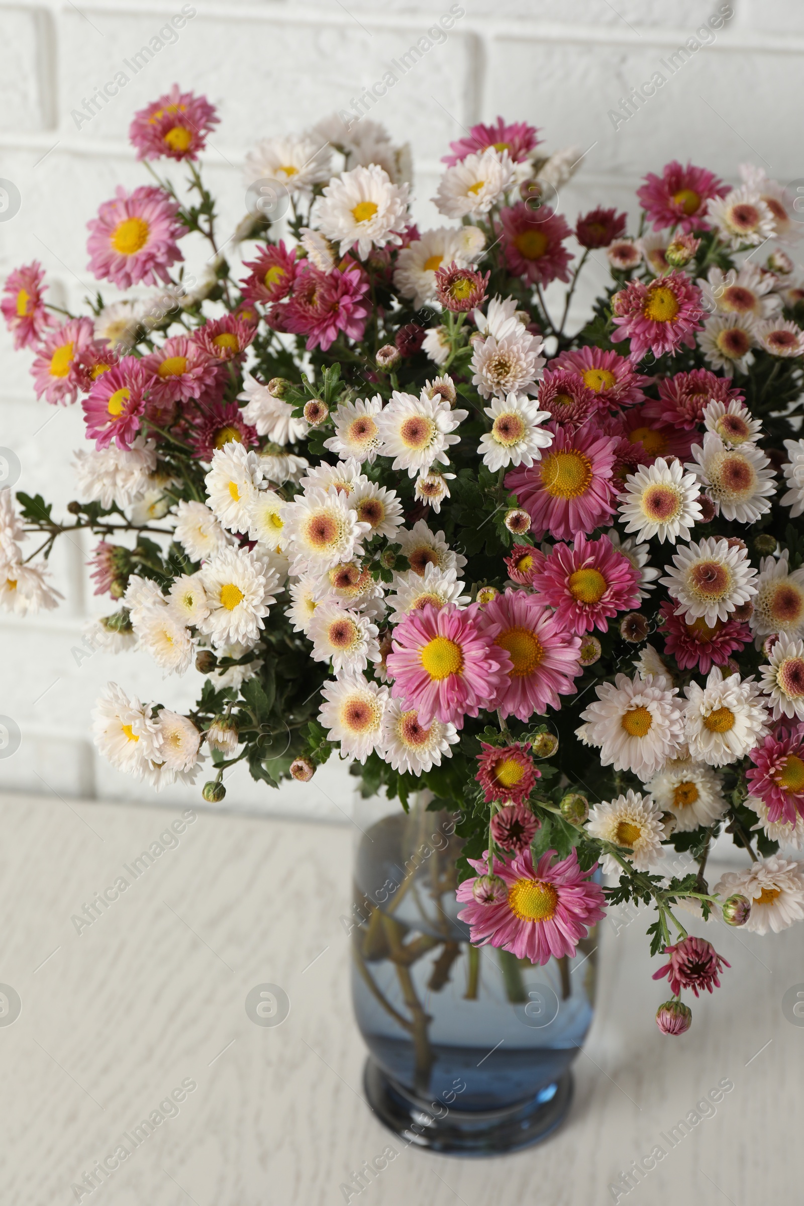 Photo of Vase with beautiful flowers on white wooden table, closeup