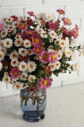 Photo of Vase with beautiful flowers on white wooden table, closeup