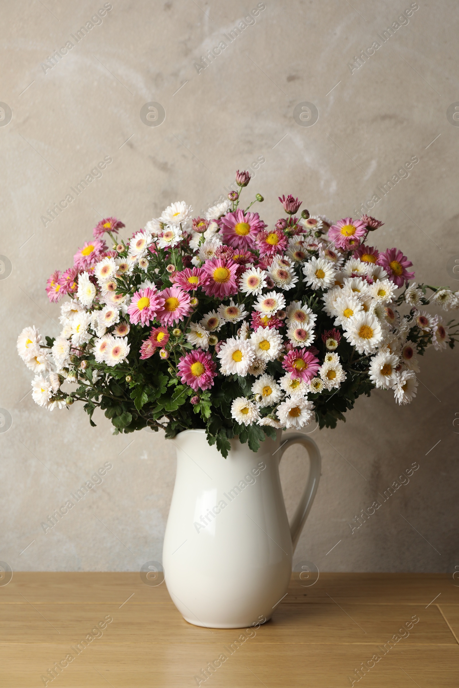 Photo of Vase with beautiful flowers on pink wooden table