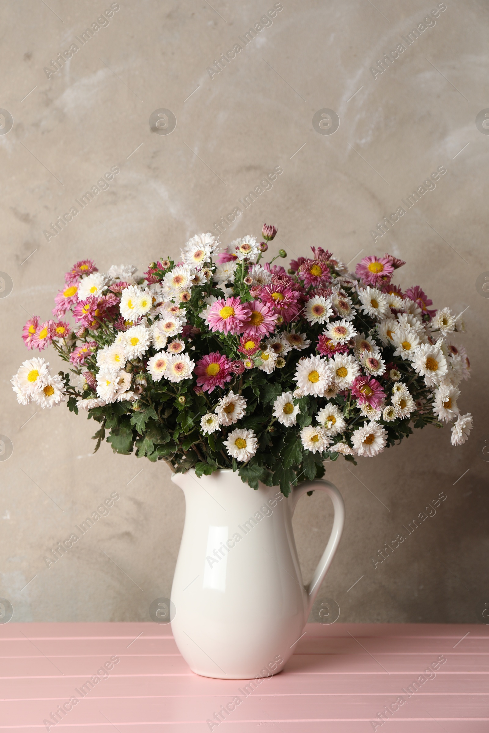 Photo of Vase with beautiful flowers on pink wooden table