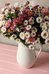 Photo of Vase with beautiful flowers on pink wooden table, closeup