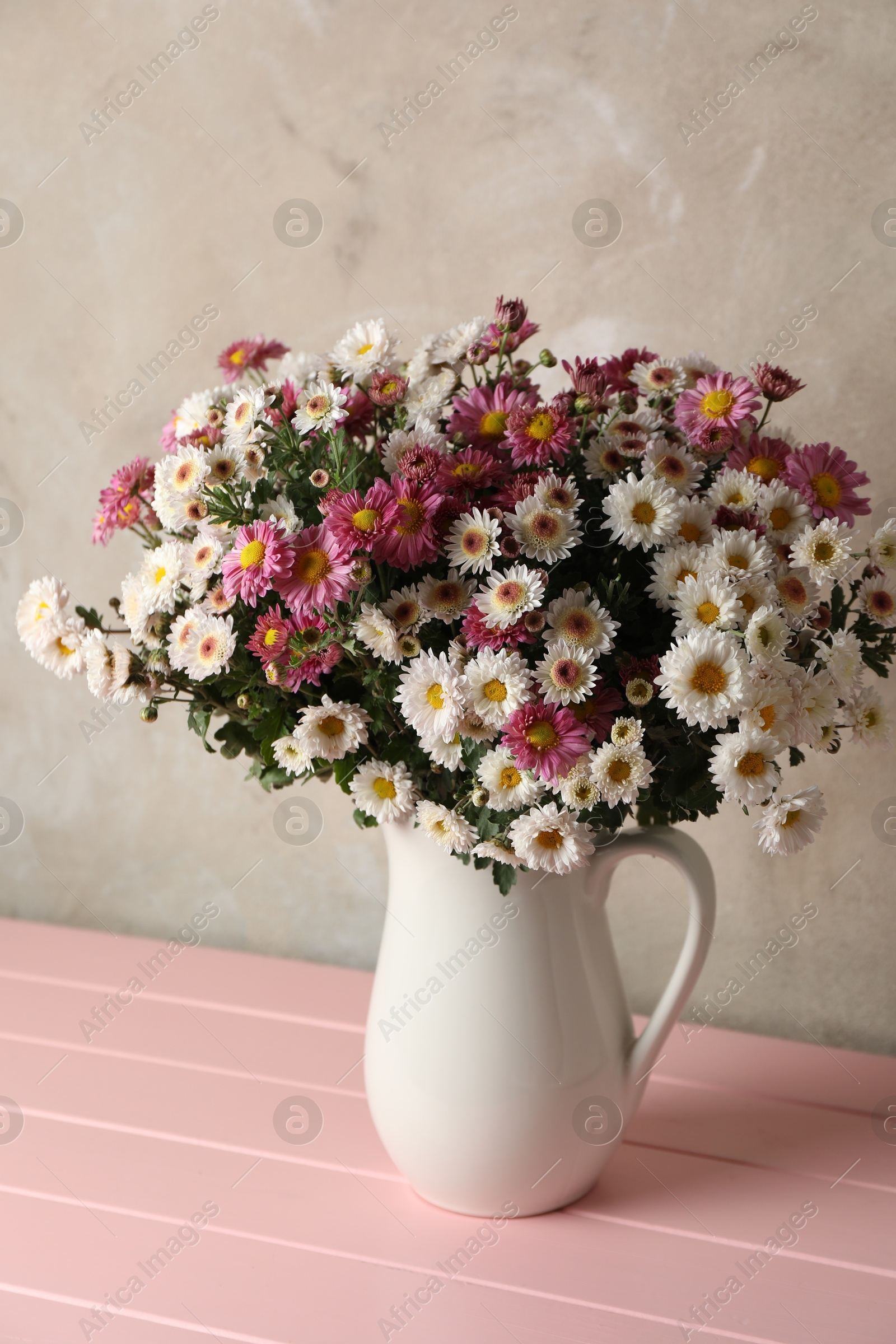 Photo of Vase with beautiful flowers on pink wooden table