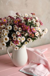 Photo of Vase with beautiful flowers and cloth on pink wooden table