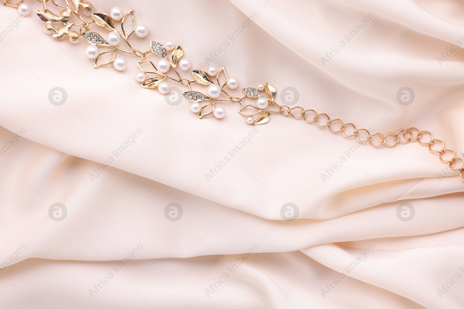 Photo of Beautiful bracelet with pearls on beige cloth, top view. Space for text