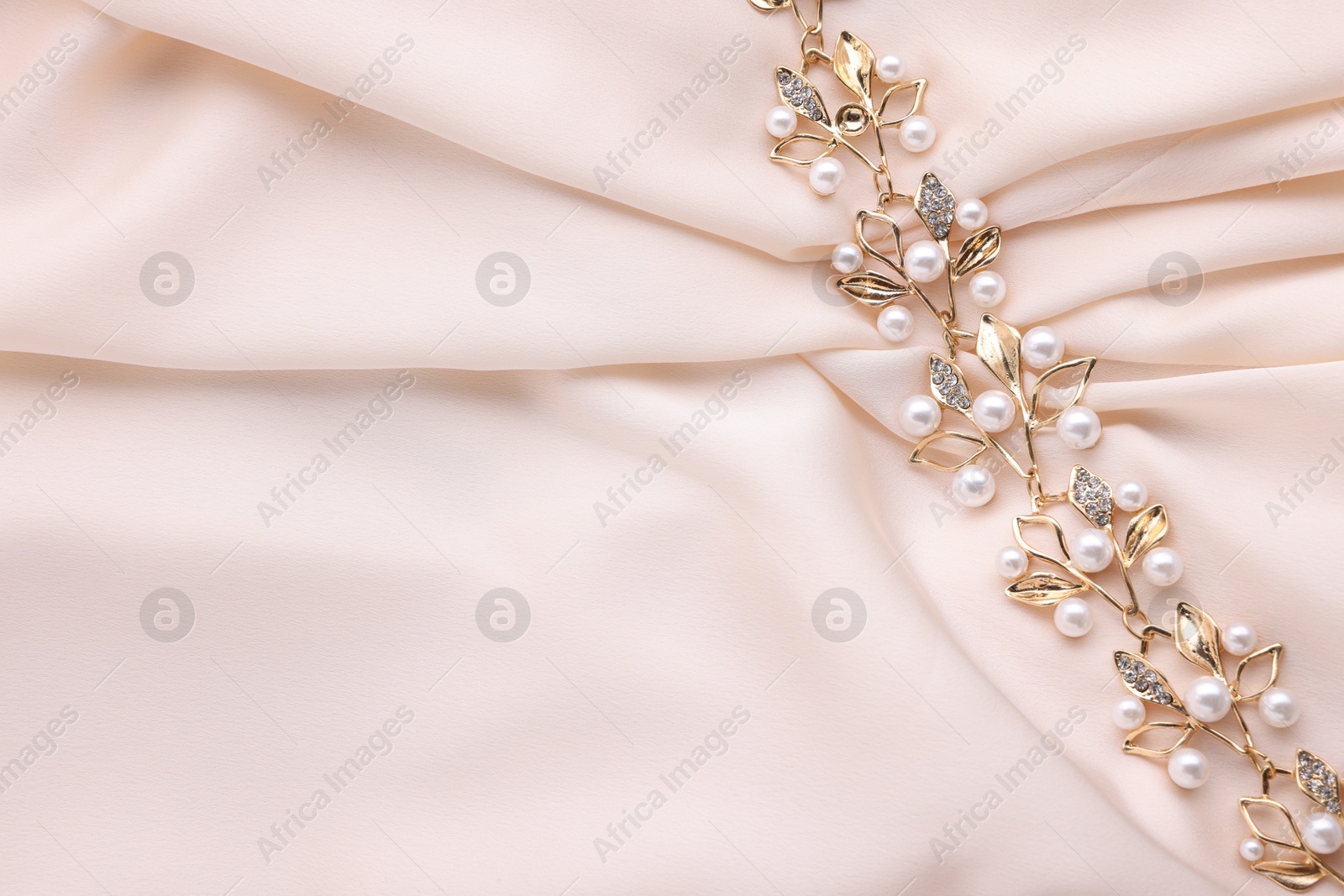 Photo of Beautiful bracelet with pearls on beige cloth, top view. Space for text