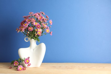 Photo of Stylish vase with beautiful flowers on wooden table. Space for text