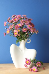 Photo of Stylish vase with beautiful flowers on wooden table