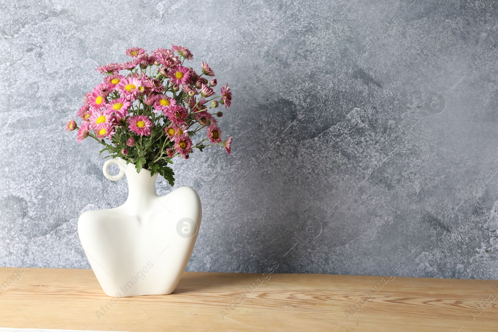 Photo of Stylish vase with beautiful flowers on wooden table. Space for text