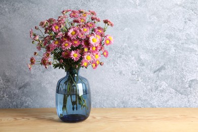 Photo of Vase with beautiful flowers on wooden table. Space for text