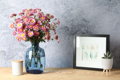 Photo of Beautiful flowers in vase and decor on wooden table