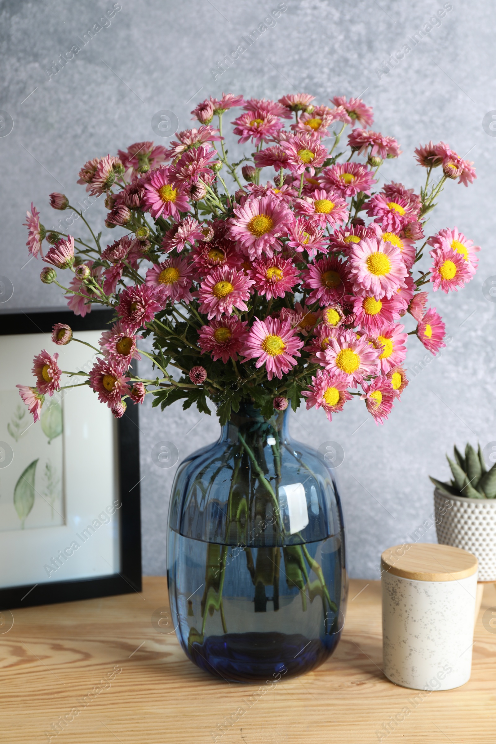 Photo of Beautiful flowers in vase and decor on wooden table