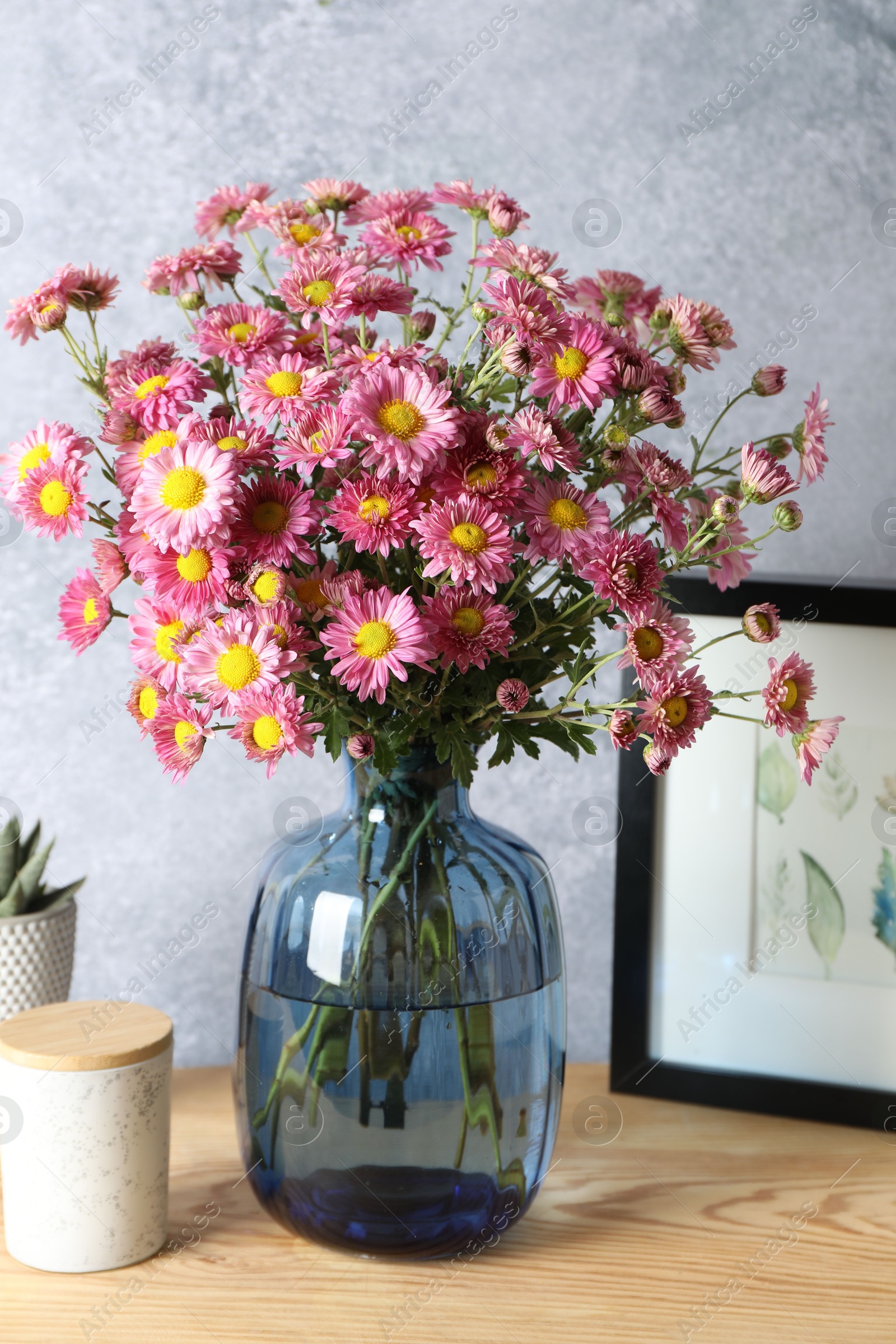 Photo of Beautiful flowers in vase and decor on wooden table