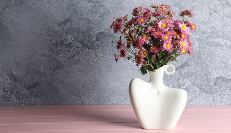 Photo of Stylish vase with beautiful flowers on pink wooden table. Space for text