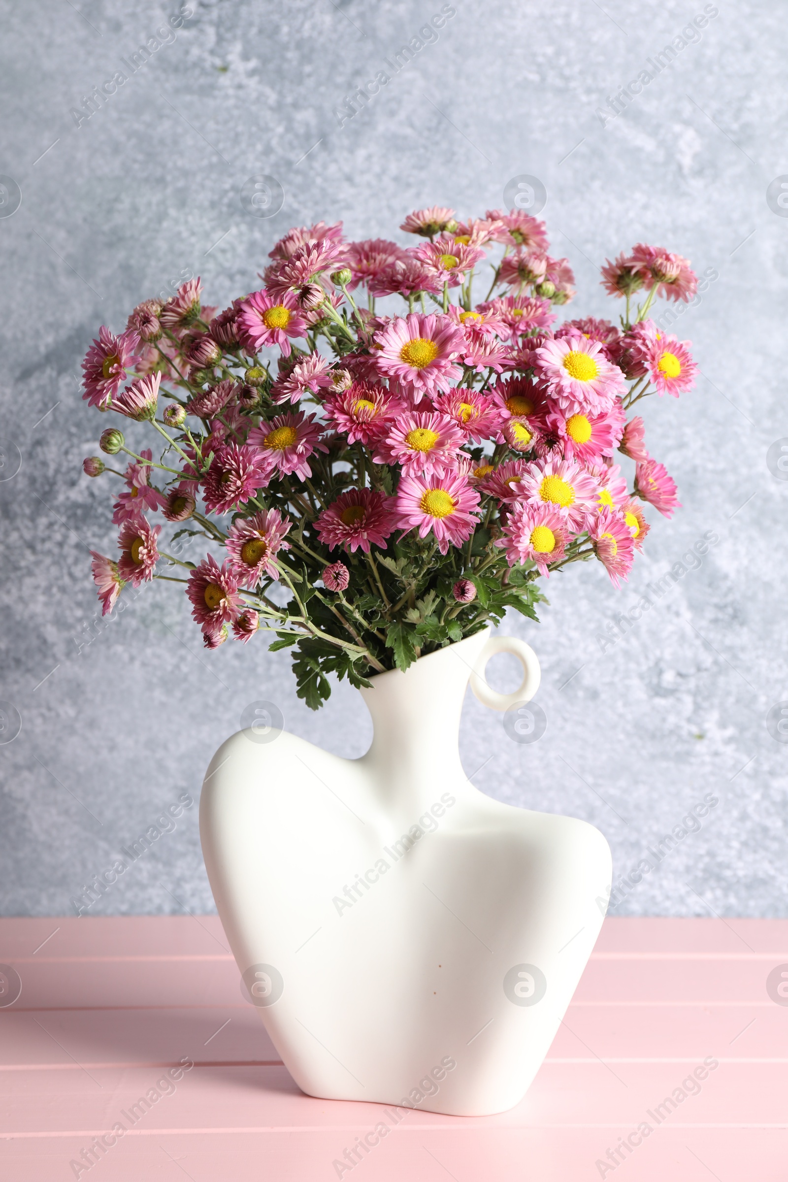 Photo of Stylish vase with beautiful flowers on pink wooden table