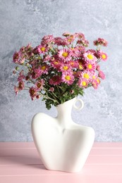 Stylish vase with beautiful flowers on pink wooden table