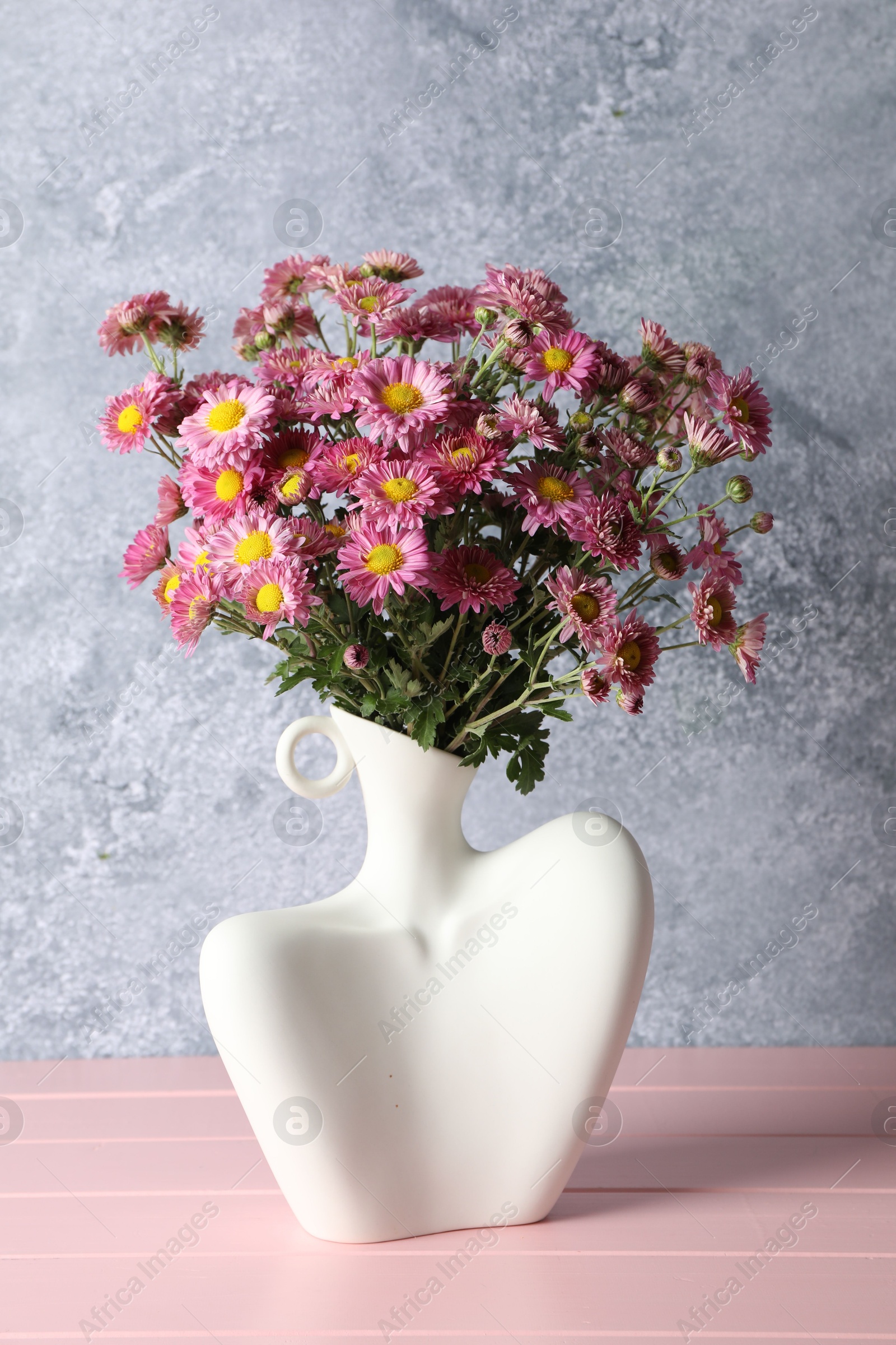 Photo of Stylish vase with beautiful flowers on pink wooden table