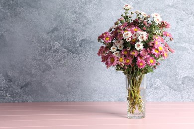 Photo of Vase with beautiful flowers on pink wooden table. Space for text