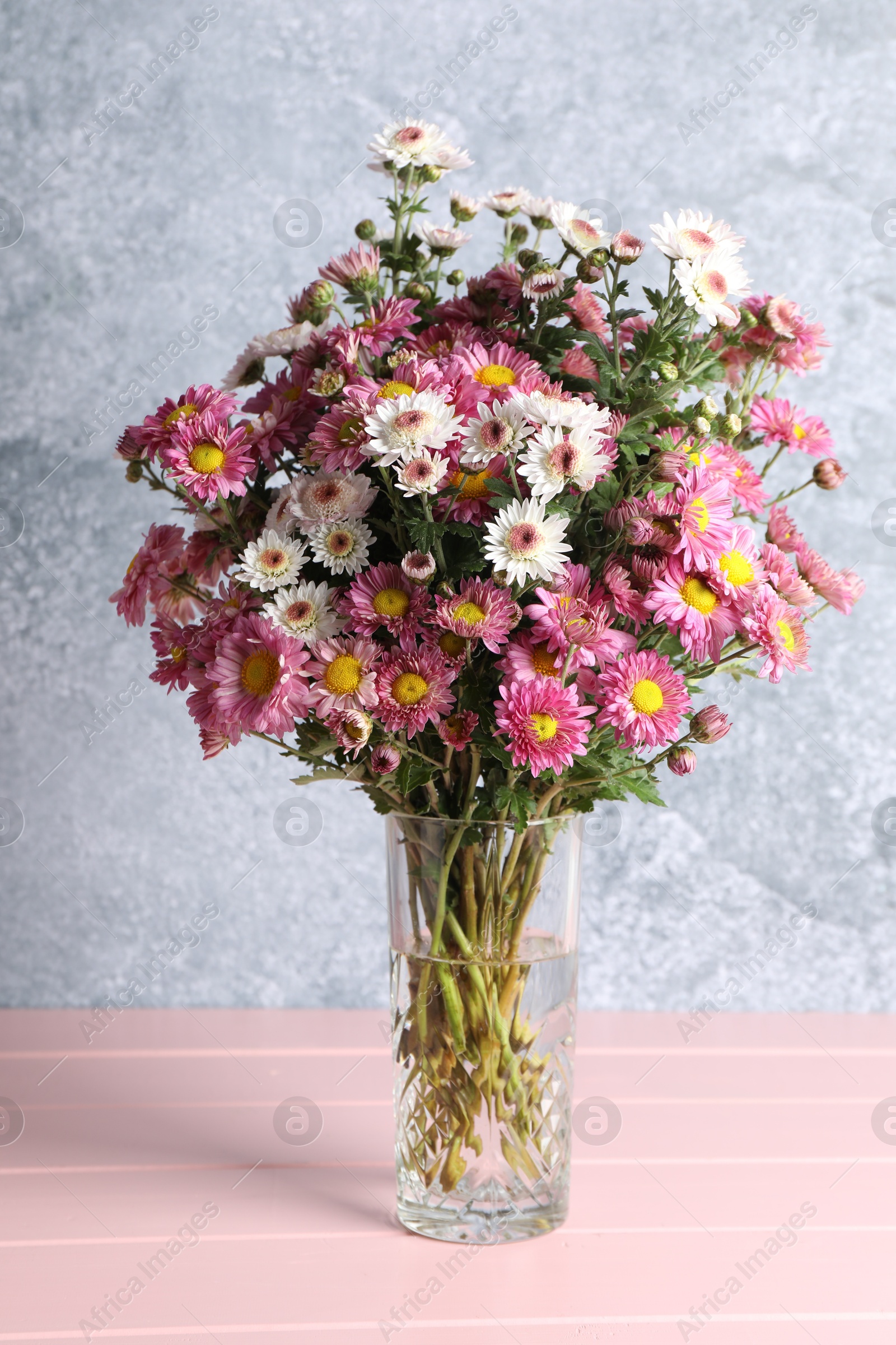 Photo of Vase with beautiful flowers on pink wooden table