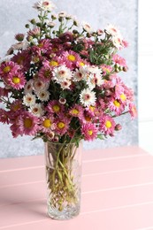 Photo of Vase with beautiful flowers on pink wooden table, closeup