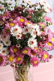 Vase with beautiful flowers on pink wooden table, closeup