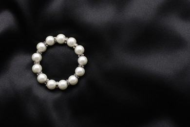 Photo of Beautiful pearl bracelet on black cloth, top view. Space for text